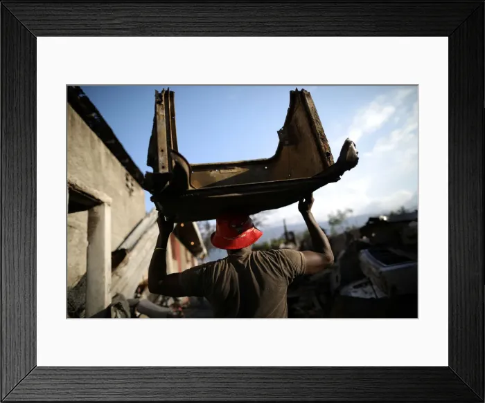 Framed Print : A man carries a piece of metal in a scrapyard in Port-au-Prince Framed Print : A man carries a piece of metal in a scrapyard in Port-au-Prince