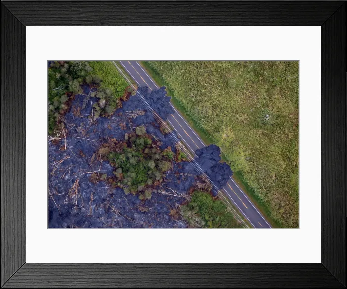 Framed Print : Lava flows across a highway on the outskirts of Pahoa