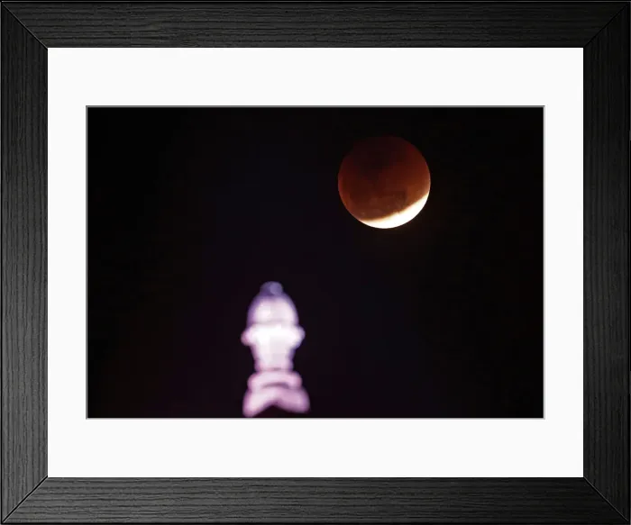 Framed Print : A lunar eclipse of a full Blue Moon is seen over the building of Indias Ministry of