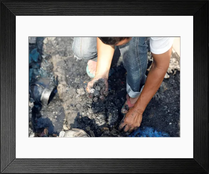 Framed Print : A fire victim gathers burnt coins on the ground inside the ruins of his familys home Framed Print : A fire victim gathers burnt coins on the ground inside the ruins of his familys home