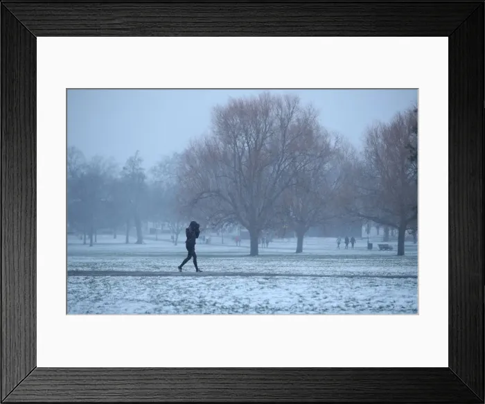 Framed Print : A walker crosses a snow-covered Clapham Common in London Framed Print : A walker crosses a snow-covered Clapham Common in London