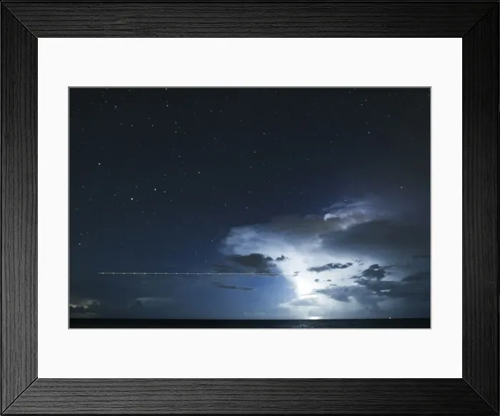 Framed Print : A long exposure shot shows a plane flying over the sea during a lightning storm on Framed Print : A long exposure shot shows a plane flying over the sea during a lightning storm on