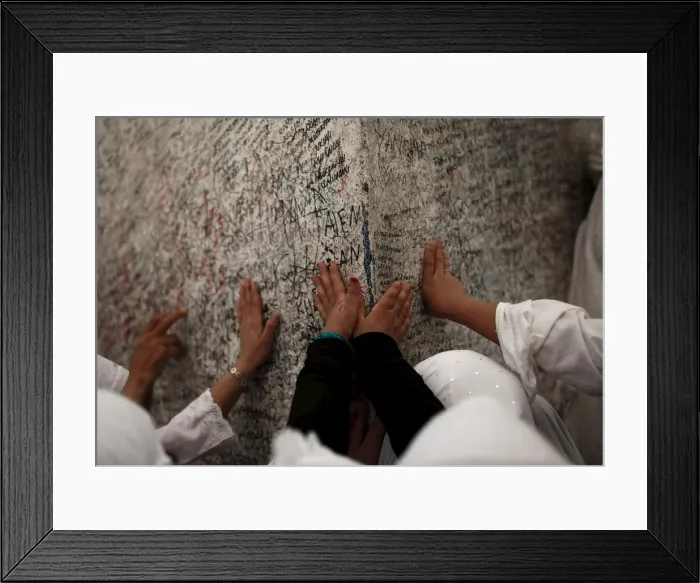 Framed Print : Muslim pilgrims touch a rock atop Mount Mercy on the plains of Arafat during the annual