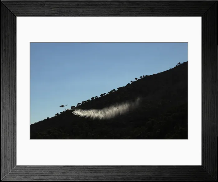 Framed Print : A helicopter drops water over a wildfire in the neighborhood of Entrerrios in Mijas