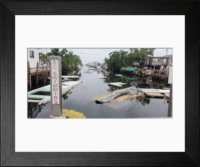 Framed Print : A debris-filled canal is seen, almost a year after Hurricane Irma, in Marathon