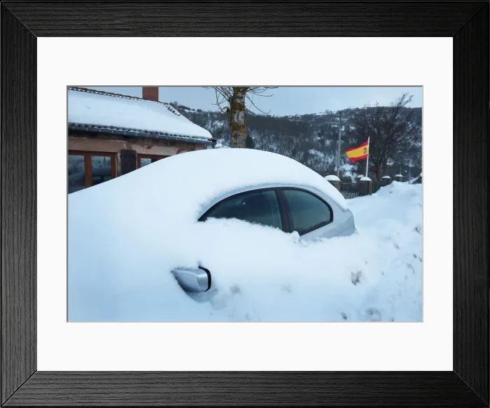 Framed Print : A snow covered car is parked next to a Spanish flag in Entrambasaguas