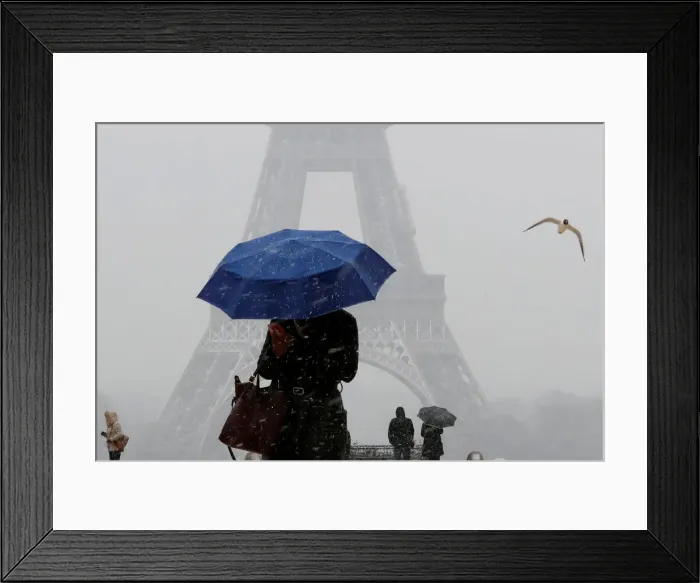 Framed Print : A woman holding an umbrella walks as snowfall near the Eiffel Tower in Paris Framed Print : A woman holding an umbrella walks as snowfall near the Eiffel Tower in Paris