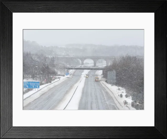 Framed Print : Snowploughs work on the M80 motorway after it was closed to clear vehicles stranded by Framed Print : Snowploughs work on the M80 motorway after it was closed to clear vehicles stranded by