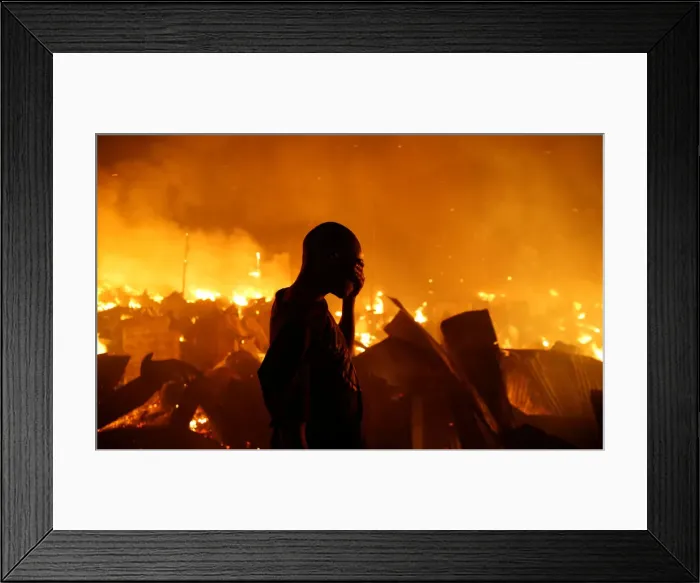 Framed Print : A resident reacts as he attempts to extinguish a fire that broke out at the Kijiji slums Framed Print : A resident reacts as he attempts to extinguish a fire that broke out at the Kijiji slums