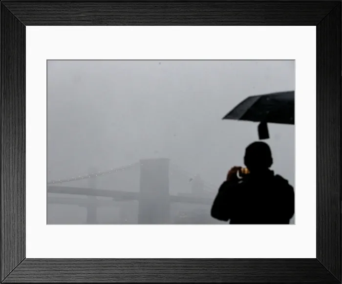 Framed Print : A man photographs the Brooklyn Bridge during a winter nor easter storm in New York Framed Print : A man photographs the Brooklyn Bridge during a winter nor easter storm in New York