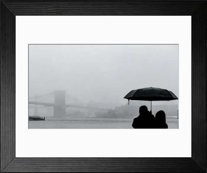 Framed Print : A couple stops to look at the Brooklyn Bridge during a winter nor easter storm in New Framed Print : A couple stops to look at the Brooklyn Bridge during a winter nor easter storm in New