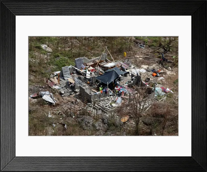 Framed Print : People sit inside a destroyed house after Hurricane Matthew hit Jeremie