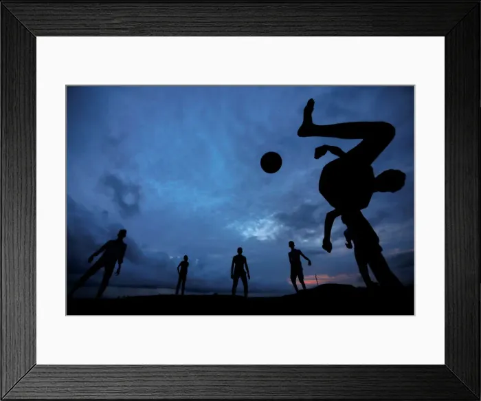 Framed Print : A boy kicks a ball as he plays soccer with his friends at Galle Dutch Fort in Galle Framed Print : A boy kicks a ball as he plays soccer with his friends at Galle Dutch Fort in Galle