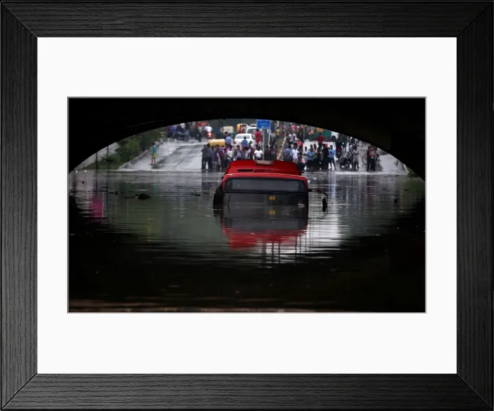 Framed Print : A bus is seen submerged on a flooded road under a railway bridge after heavy rains in New