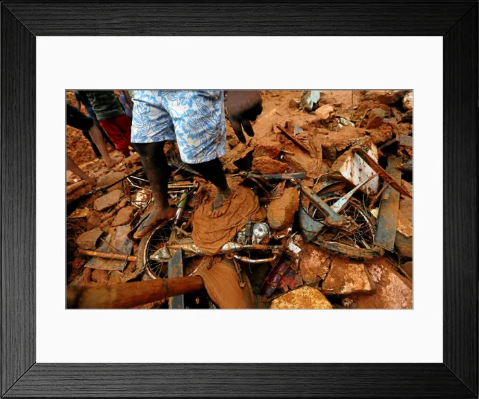 Framed Print : A man stands on top of a damaged bike during a rescue mission at the site of a landslide Framed Print : A man stands on top of a damaged bike during a rescue mission at the site of a landslide