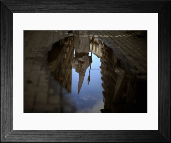 Framed Print : A penitent is reflected in a puddle of water after rain fell at the Humildad Framed Print : A penitent is reflected in a puddle of water after rain fell at the Humildad