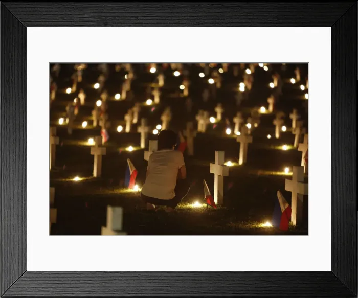 Framed Print : A woman offers a prayer near the grave of her loved one in a cemetery during