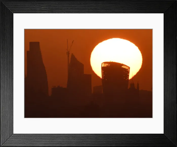 Framed Print : The sun is seen rising over skyscrapers in the City of London financial district in