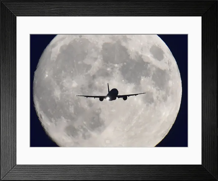 Framed Print : A passenger plane passes in front of the full moon as it makes a final landing approach