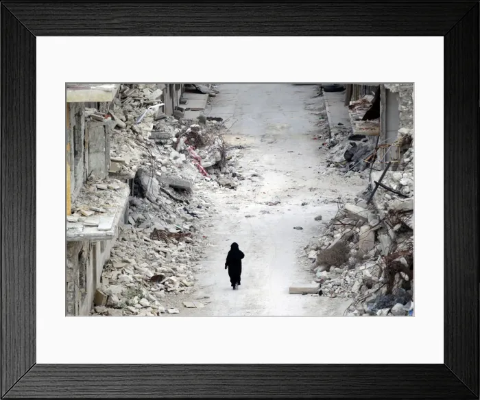 Framed Print : A woman walks past damaged buildings in the rebel-controlled area of Maaret al-Numan town Framed Print : A woman walks past damaged buildings in the rebel-controlled area of Maaret al-Numan town