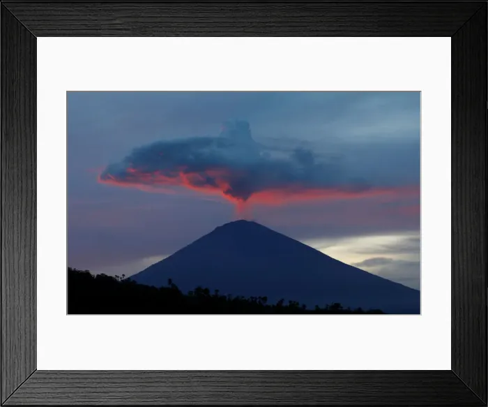 Framed Print : A plume of smoke above Mount Agung volcano is illuminated at sunset as seen from Amed
