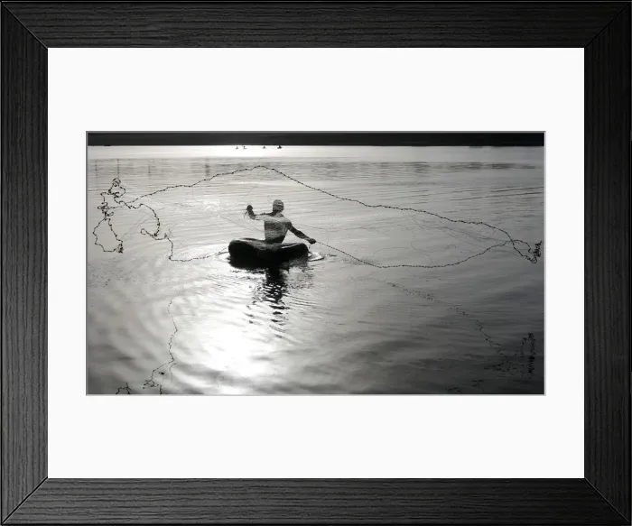 Framed Print : Fisherman floating on a rubber tube throws a net to catch fish from the waters of Framed Print : Fisherman floating on a rubber tube throws a net to catch fish from the waters of