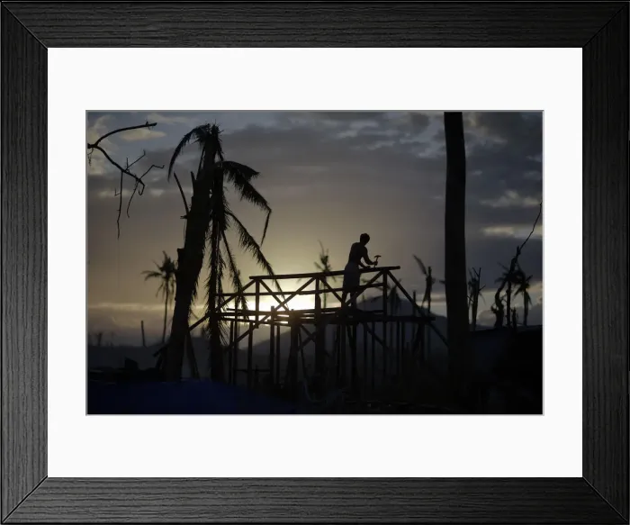 Framed Print : A man is silhouetted as he builds a wooden house in an area destroyed by Typhoon Haiyan Framed Print : A man is silhouetted as he builds a wooden house in an area destroyed by Typhoon Haiyan