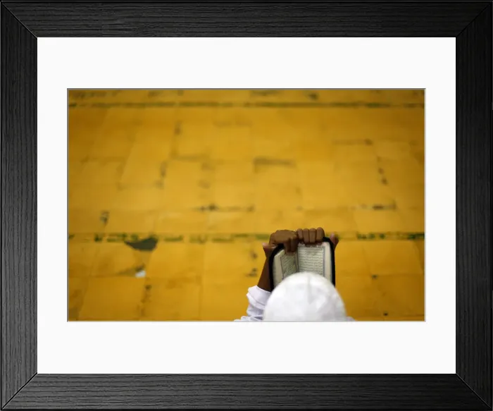 Framed Print : A student reads the Koran before morning prayer on the holy month of Ramadan