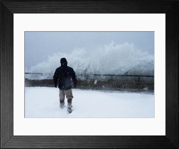 Framed Print : A man watches as ocean waves overtop the seawall during a winter snow storm in the Boston