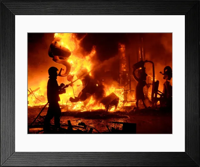 Framed Print : A fireman sprays water at figures of a monument as it burns during the finale of