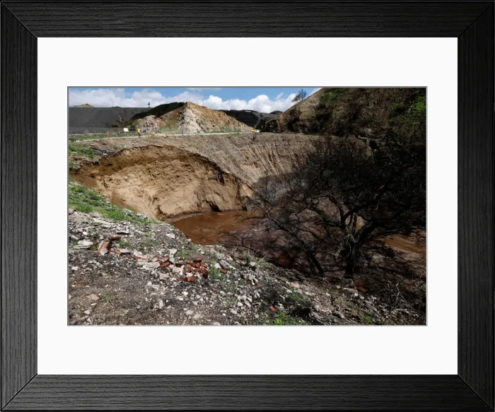 Framed Print : Personnel is pictured around a portion of a hillside which gave in due to heavy rain in a Framed Print : Personnel is pictured around a portion of a hillside which gave in due to heavy rain in a