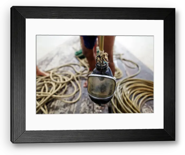 Framed Print : A diver holds his mask on a small boat on Yangon River after searching for coal
