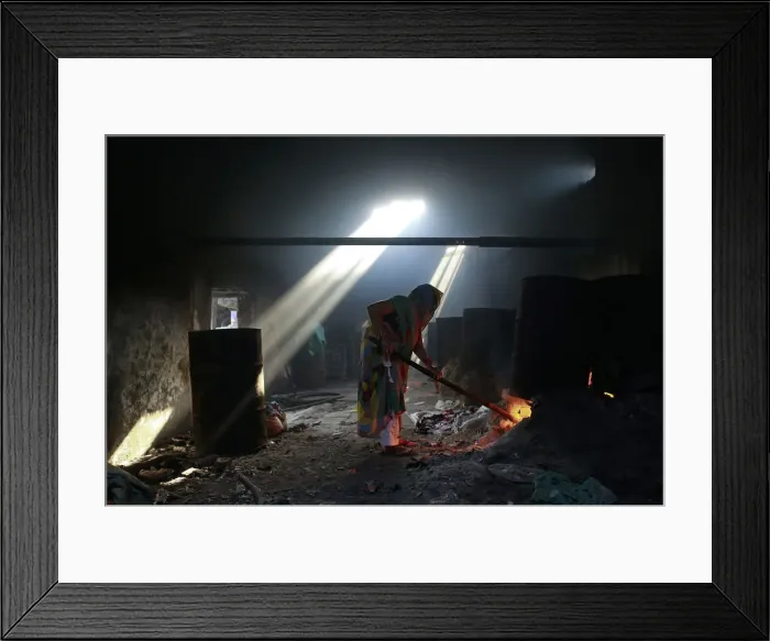 Framed Print : A woman lights fire to heat water for soaking clothes at a laundry in Mumbai Framed Print : A woman lights fire to heat water for soaking clothes at a laundry in Mumbai