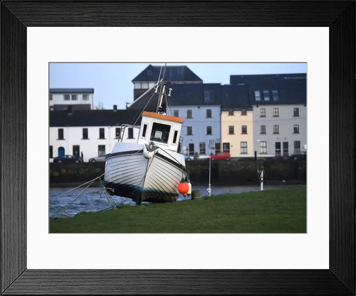 Framed Print : A boat is stranded on the edge of a pier after it was washed there by floods in Galway