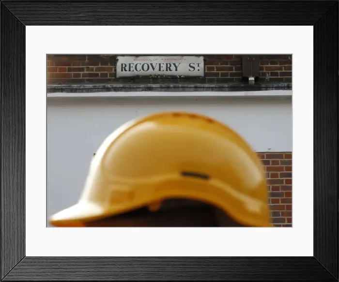Framed Print : A construction worker walks past a street sign in south London Framed Print : A construction worker walks past a street sign in south London