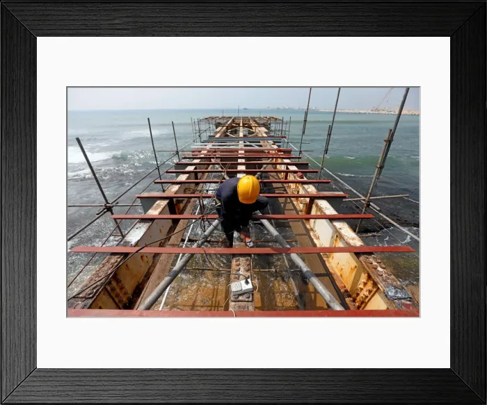 Framed Print : A labourer works at a construction site of a bridge on the sea in Colombo Framed Print : A labourer works at a construction site of a bridge on the sea in Colombo