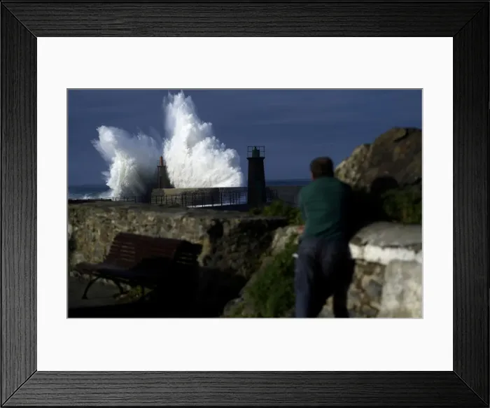 Framed Print : A man looks at waves as they crash against a lighthouse in the port town of Viavelez Framed Print : A man looks at waves as they crash against a lighthouse in the port town of Viavelez