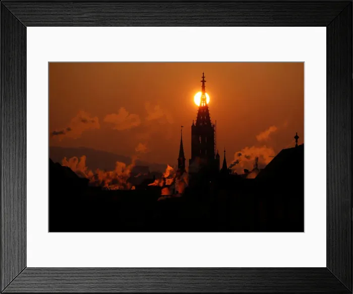 Framed Print : The sun rises behind the Muenster Cathedral during a cold morning in Bern