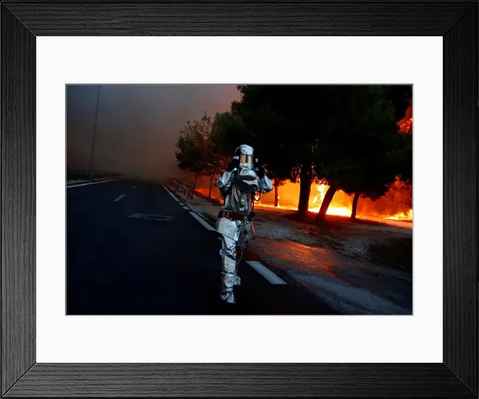 Framed Print : A firefighter wears a flame resistant uniform as wildfire burns in the town of Rafina