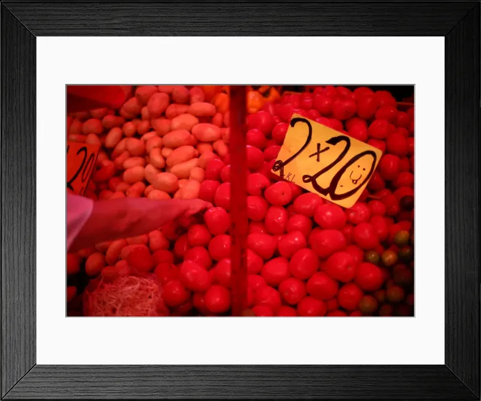Framed Print : A woman selects vegetables next to sign that displayed the price of tomatoes at a store Framed Print : A woman selects vegetables next to sign that displayed the price of tomatoes at a store