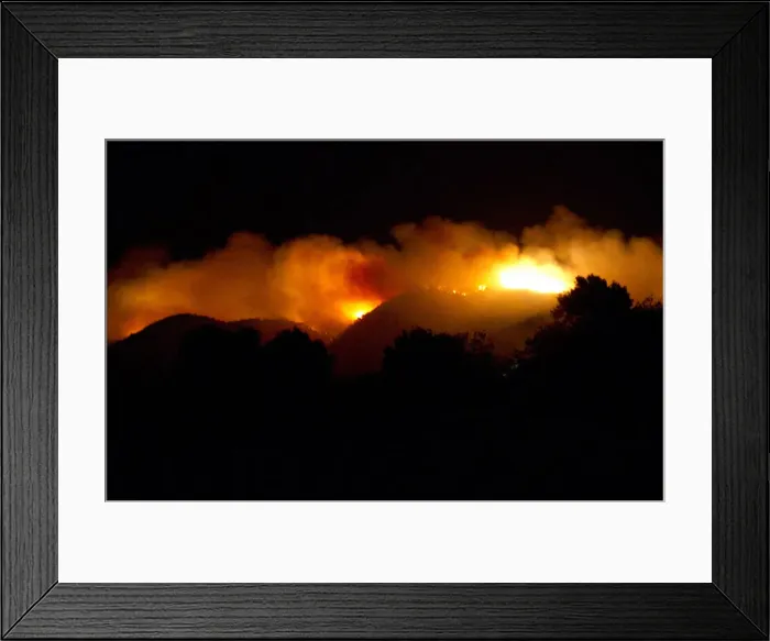 Framed Print : Smoke rises from a burning forest near the village of Sant Joan de Labritja on