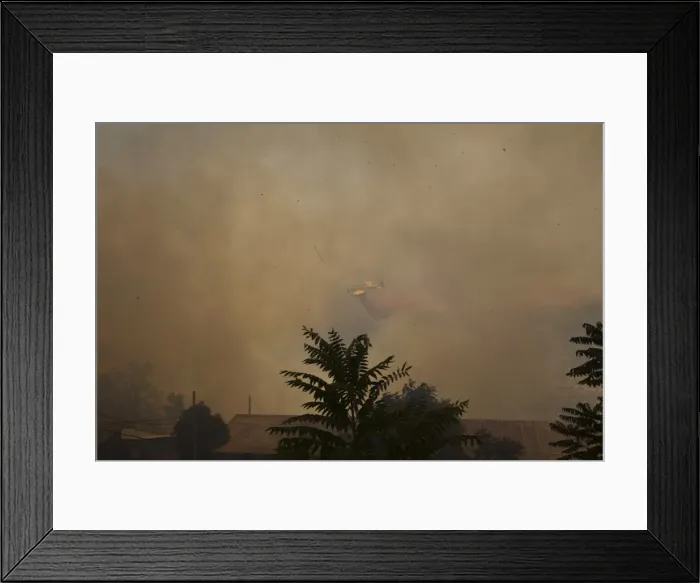 Framed Print : A firefighting plane drops fire retardant during a forest fire in Even Sapir