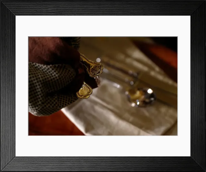Framed Print : A woman polishes silver cutlery at her home in Valletta