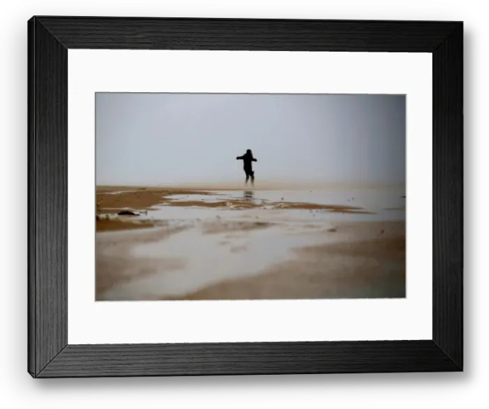 Framed Print : A woman walks against the wind during a storm in Zikim beach Framed Print : A woman walks against the wind during a storm in Zikim beach