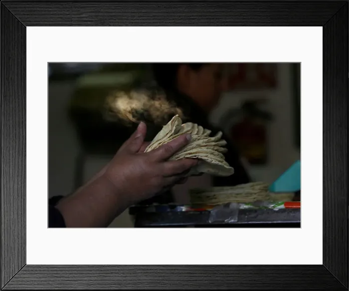 Framed Print : Woman holds freshly made corn tortillas at a tortilla factory in Mexico City