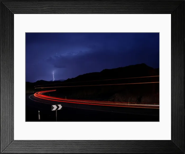 Framed Print : Cars drive as lightning strikes near the site where a group of Israeli youths was swept
