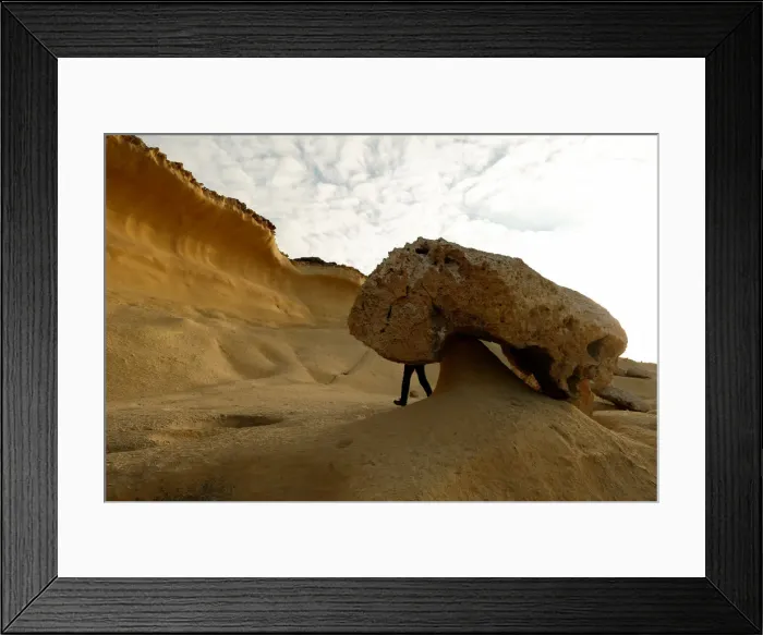 Framed Print : A tourist hikes past the so-called Mushroom Rock, formed by years of weathering Framed Print : A tourist hikes past the so-called Mushroom Rock, formed by years of weathering