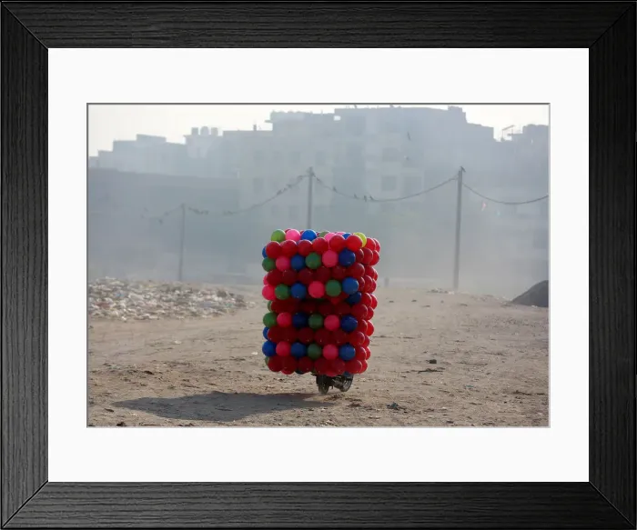 Framed Print : A man carries childrens coloured plastic balls on his motorcycle in Delhi