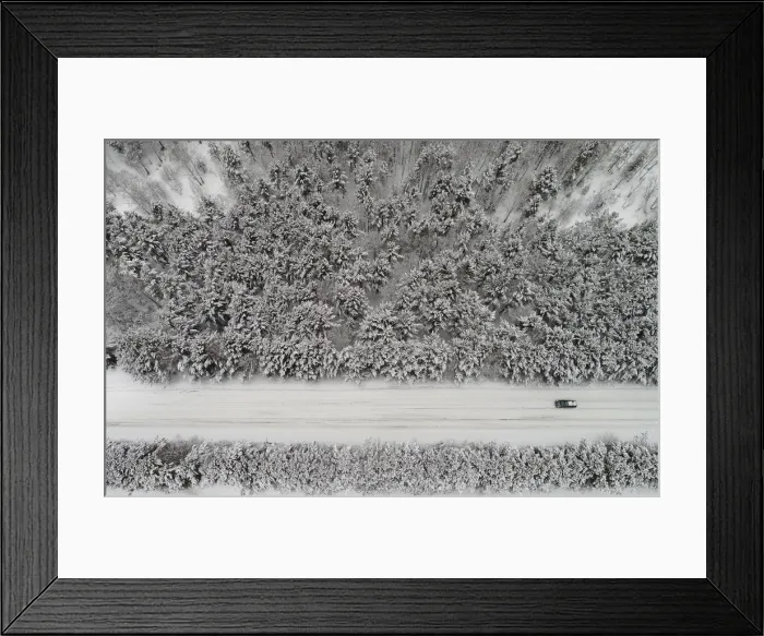 Framed Print : An aerial view shows a car driving along a forest road after snowfall outside Krasnoyarsk
