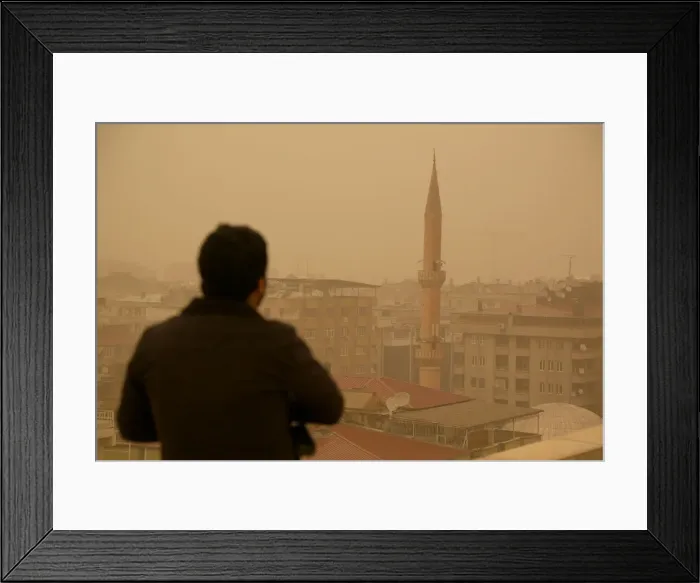 Framed Print : A man stands on top of a building during a dust storm in Diyarbakir